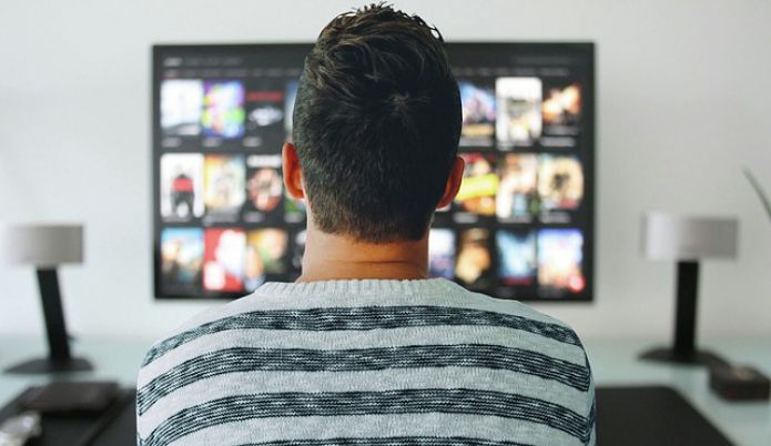 man behind a computer monitor watching a video